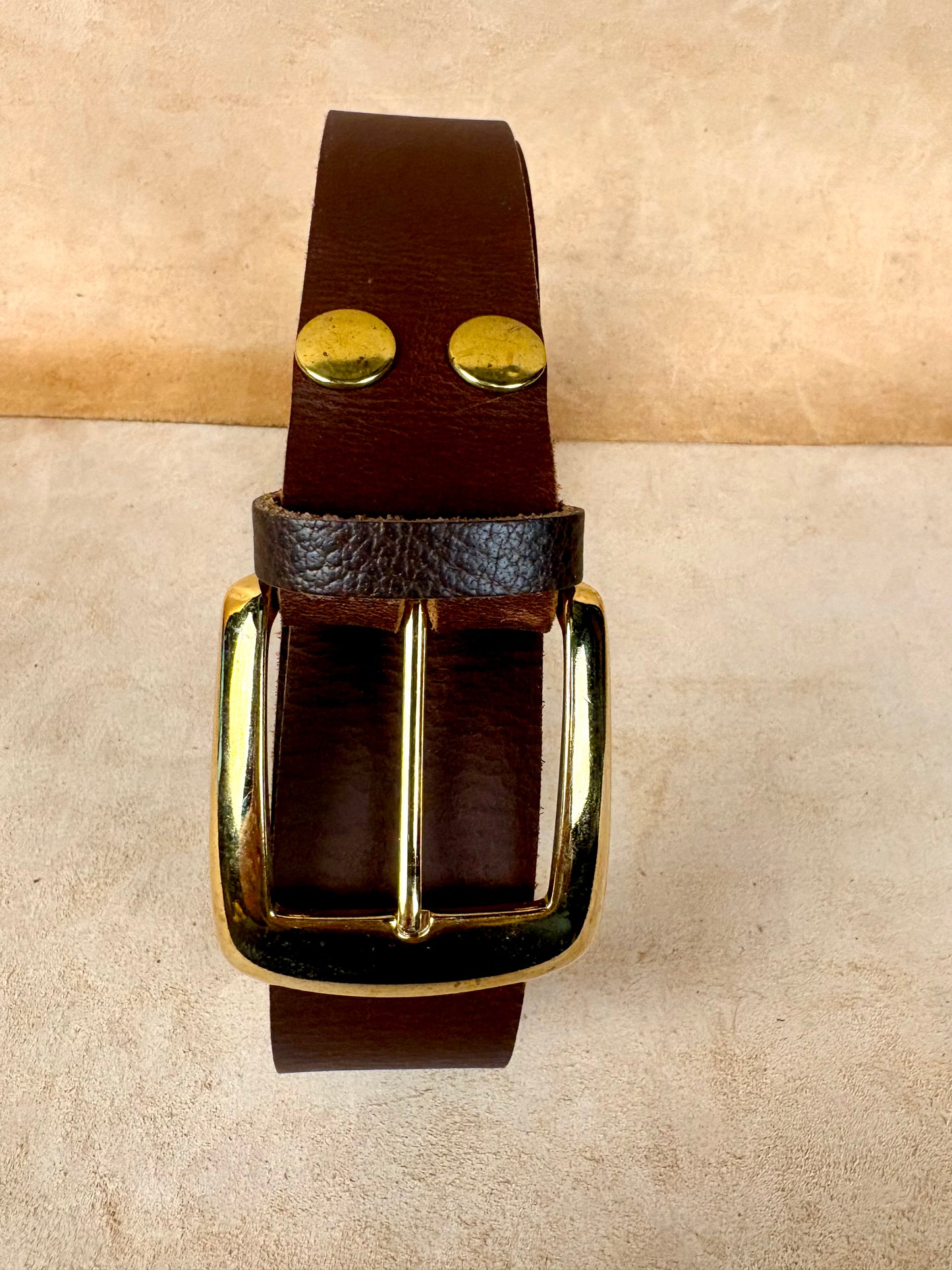 brown leather belt with gold buckle and rivets