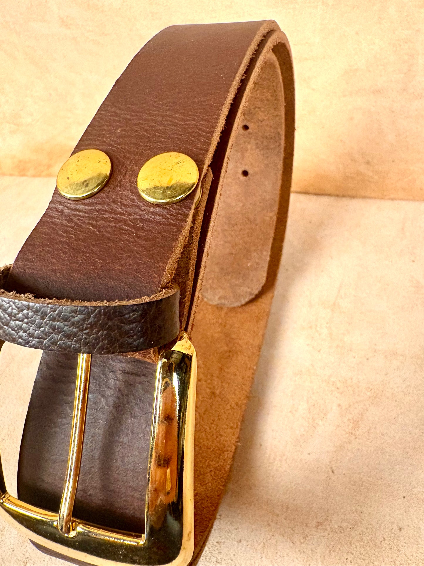 brown leather belt with gold buckle and rivets