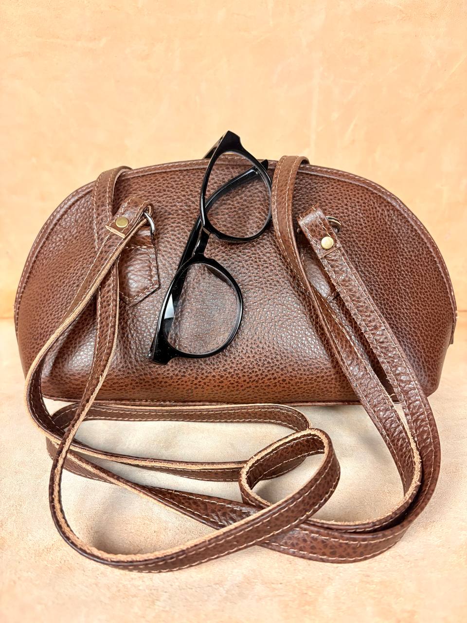 Nomad Arc leather handbag lifestyle detail with glasses

